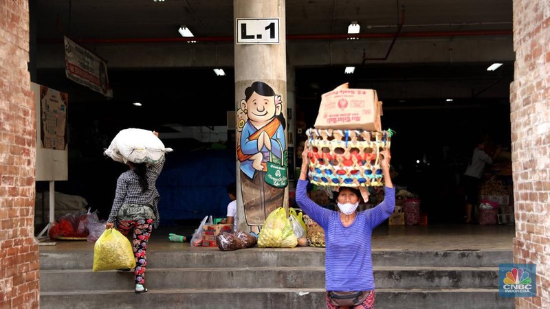 Pembeli membayar belanjaanya dengan menggunakan aplikasi pembayaran digital QRIS (QR Code Indonesian Standard) untuk transaksi dagang di pasar Badung, Denpasar, Bali, Selasa, (30/8/2022). (CNBC Indonesia/Muhammad Sabki)