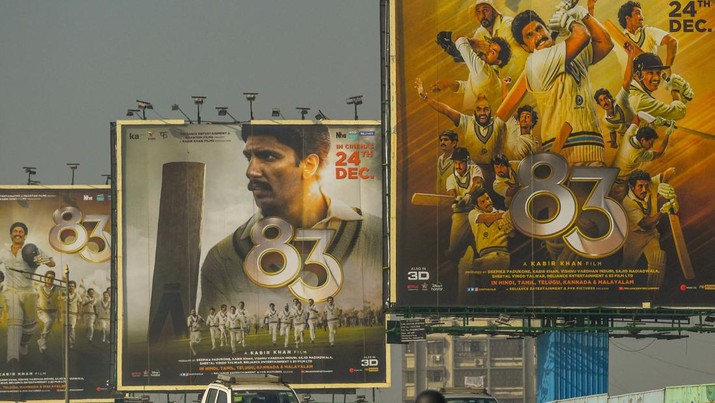 Kendaraan bergerak melewati papan iklan film Bollywood '83', yang didasarkan pada kemenangan piala dunia kriket pertama India pada tahun 1983, di Mumbai pada 24 Desember 2021. (AFP via Getty Images/INDRANIL MUKHERJEE)