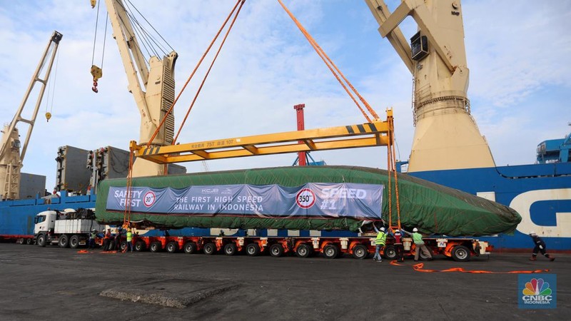 Pekerja dengan menggunakan alat berat melakukan bongkar muat Electric Multiple Unit (EMU) atau kereta untuk proyek Kereta Cepat Jakarta-Bandung (KCJB) yang tiba di Pelabuhan Tanjung Priok, Jumat (2/8/2022). (CNBC Indoensia/Andrean Kristianto)