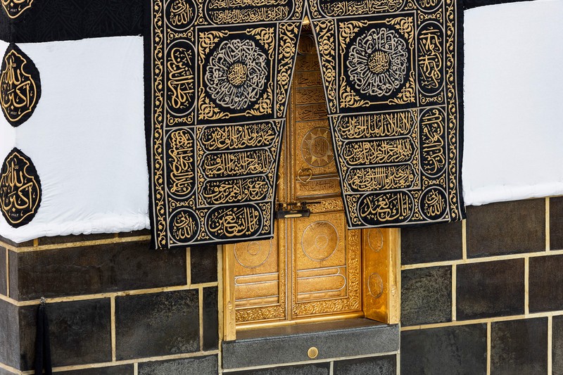 1241744336 This picture taken on July 6, 2022 shows a close-up view of the Kiswa, the cloth used to cover the Kaaba, and the Kaaba's gold doors underneath, at the Grand Mosque in the Muslim holy city of Mecca during the annual Hajj pilgrimage. - One million fully vaccinated Muslims, including 850,000 from abroad, are allowed at this year's hajj in the city of Mecca, a big rise after two years of drastically curtailed numbers due to policies to stop the spread of infection. (Photo by AFP) (Photo by -/AFP via Getty Images)