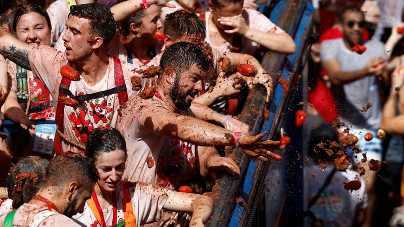 A reveler plays in tomato pulp during the annual 