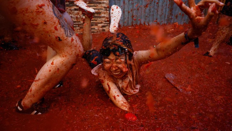 A reveler plays in tomato pulp during the annual 
