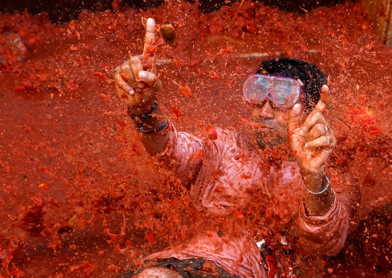 A reveler plays in tomato pulp during the annual 