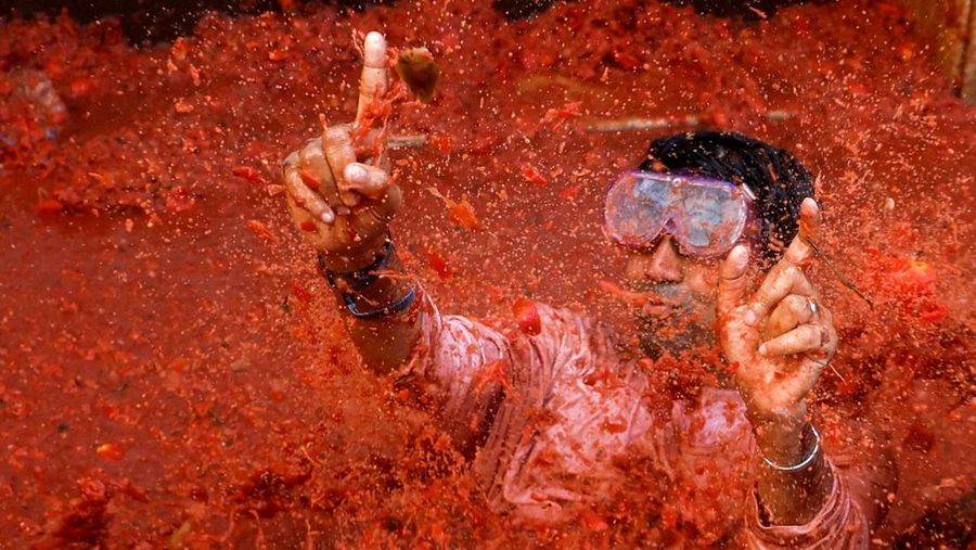 A reveler plays in tomato pulp during the annual 