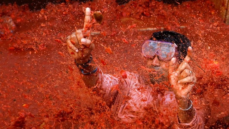 A reveler plays in tomato pulp during the annual 