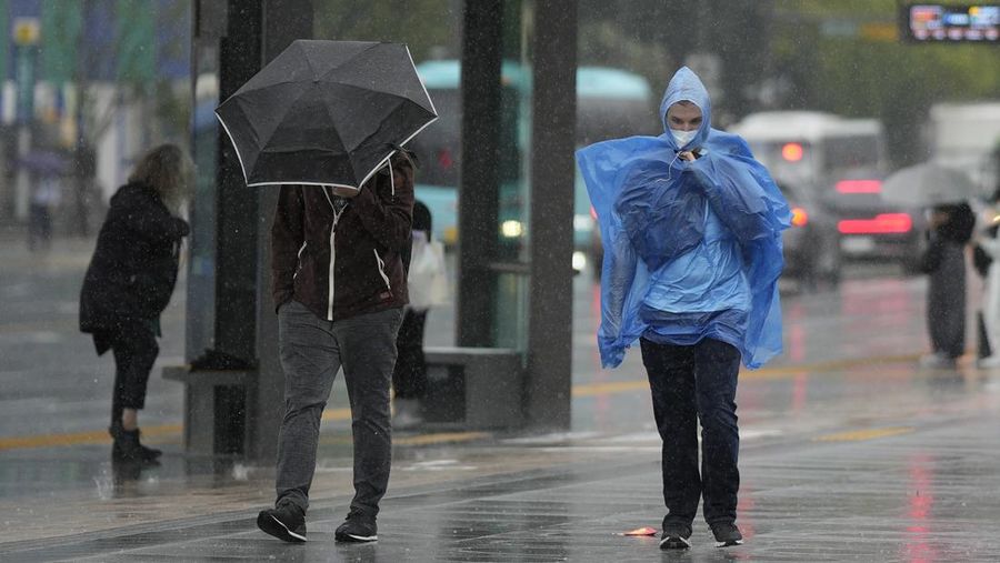 Seorang pria berjalan melewati angin kencang yang disebabkan oleh topan Hinnamnor di pulau Jeju, Korea Selatan, Senin (5/9/2022), (Yonhap via REUTERS)