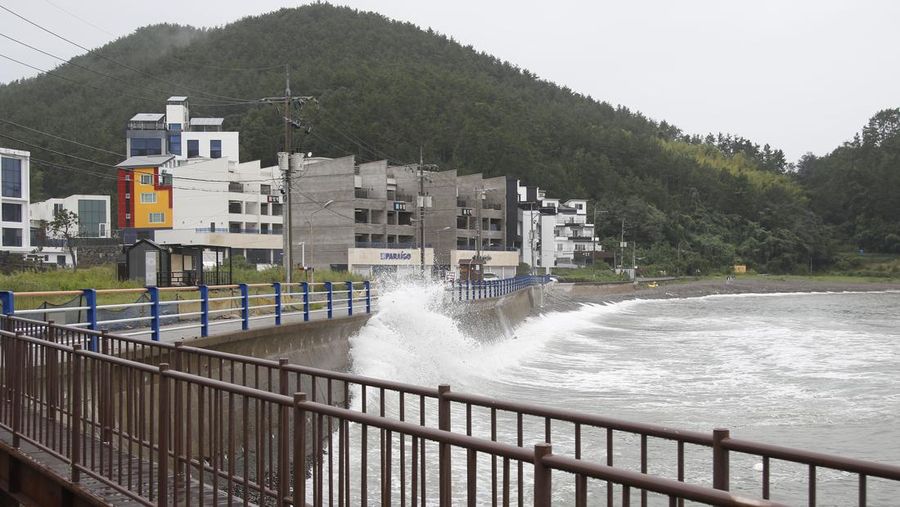 Seorang pria berjalan melewati angin kencang yang disebabkan oleh topan Hinnamnor di pulau Jeju, Korea Selatan, Senin (5/9/2022), (Yonhap via REUTERS)