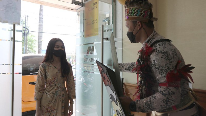 Petugas Customer Service Bank Mega memakai kostum adat Suku Dayak saat memberikan pelayanan m banking kepada salah seorang nasabah di KCP Jakarta Cinere, Kota Depok, Jawa Barat, Senin (5/9/2022). Sehubungan dengan pelaksanaan Hari Pelanggan Nasional, karyawan Bank Mega di seluruh Kantor Cabang dan Kantor Cabang Pembantu sengaja memakai kostum dengan beragam tema guna memberikan pengalaman yang berbeda kepada para nasabah yang berkunjung. (Dok. Bank Mega)