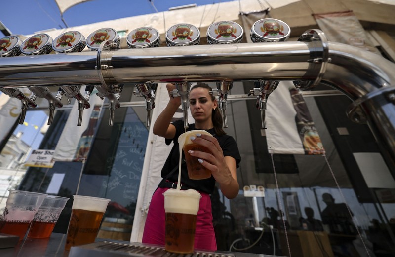 Bir Halal Palestina Taybeh Seorang bartender melayani pengunjung pada festival bir tahunan Oktoberfest di desa Taybeh di desa Taybeh, sebelah timur kota Ramallah Tepi Barat, Palestina, Jumat (2/92/2022). Bir Taybeh dibuat dari buah anggur yang tumbuh di kebun anggur dekat Kota Birzeit, West Bank, sekitar 10 kilometer timur laut Ramallah. Bir Taybeh diseduh dalam jumlah kecil, tanpa menggunakan bahan pengawet atau gula tambahan. Taybeh Brewing Company didirikan oleh Nadim Khoury dan keluarganya pada 1994 di West Bank, Palestina dan kini diteruskan oleh seorang wanita bernama Madees Khoury, (Photo by ABBAS MOMANI/AFP via Getty Images).