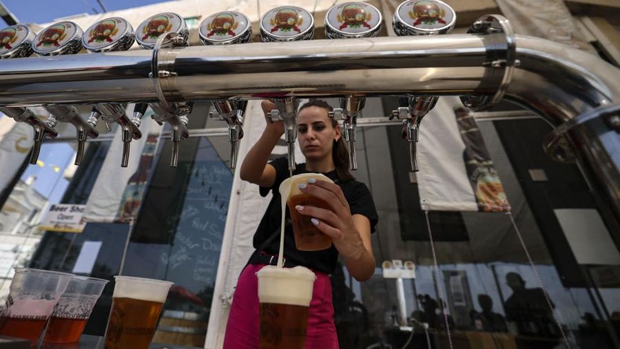 Seorang bartender melayani pengunjung pada festival bir tahunan Oktoberfest di desa Taybeh di desa Taybeh, sebelah timur kota Ramallah Tepi Barat, Palestina, Jumat (2/92/2022). Bir Taybeh dibuat dari buah anggur yang tumbuh di kebun anggur dekat Kota Birzeit, West Bank, sekitar 10 kilometer timur laut Ramallah. Bir Taybeh diseduh dalam jumlah kecil, tanpa menggunakan bahan pengawet atau gula tambahan. Taybeh Brewing Company didirikan oleh Nadim Khoury dan keluarganya pada 1994 di West Bank, Palestina dan kini diteruskan oleh seorang wanita bernama Madees Khoury, (Photo by ABBAS MOMANI/AFP via Getty Images).