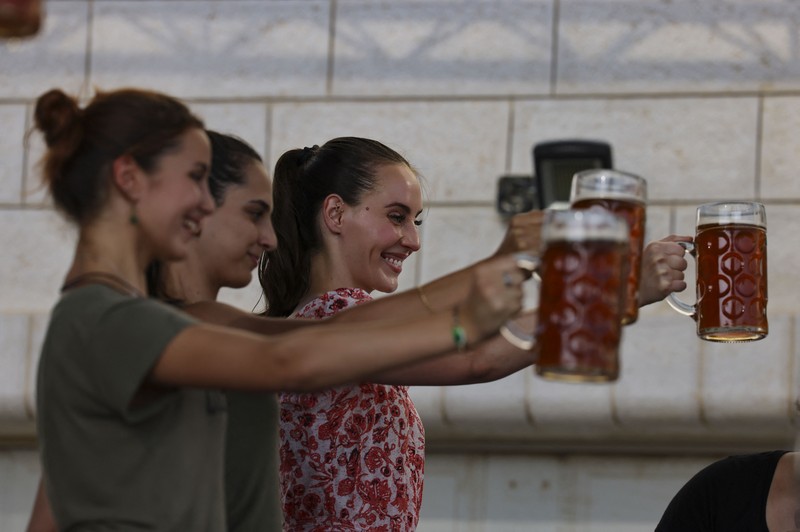 Bir Halal Palestina Taybeh Seorang bartender melayani pengunjung pada festival bir tahunan Oktoberfest di desa Taybeh di desa Taybeh, sebelah timur kota Ramallah Tepi Barat, Palestina, Jumat (2/92/2022). Bir Taybeh dibuat dari buah anggur yang tumbuh di kebun anggur dekat Kota Birzeit, West Bank, sekitar 10 kilometer timur laut Ramallah. Bir Taybeh diseduh dalam jumlah kecil, tanpa menggunakan bahan pengawet atau gula tambahan. Taybeh Brewing Company didirikan oleh Nadim Khoury dan keluarganya pada 1994 di West Bank, Palestina dan kini diteruskan oleh seorang wanita bernama Madees Khoury, (Photo by ABBAS MOMANI/AFP via Getty Images).
