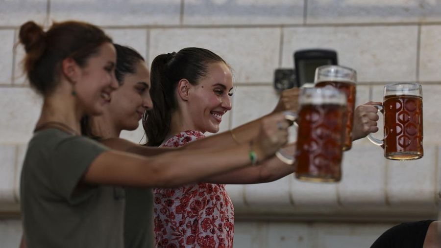 Seorang bartender melayani pengunjung pada festival bir tahunan Oktoberfest di desa Taybeh di desa Taybeh, sebelah timur kota Ramallah Tepi Barat, Palestina, Jumat (2/92/2022). Bir Taybeh dibuat dari buah anggur yang tumbuh di kebun anggur dekat Kota Birzeit, West Bank, sekitar 10 kilometer timur laut Ramallah. Bir Taybeh diseduh dalam jumlah kecil, tanpa menggunakan bahan pengawet atau gula tambahan. Taybeh Brewing Company didirikan oleh Nadim Khoury dan keluarganya pada 1994 di West Bank, Palestina dan kini diteruskan oleh seorang wanita bernama Madees Khoury, (Photo by ABBAS MOMANI/AFP via Getty Images).