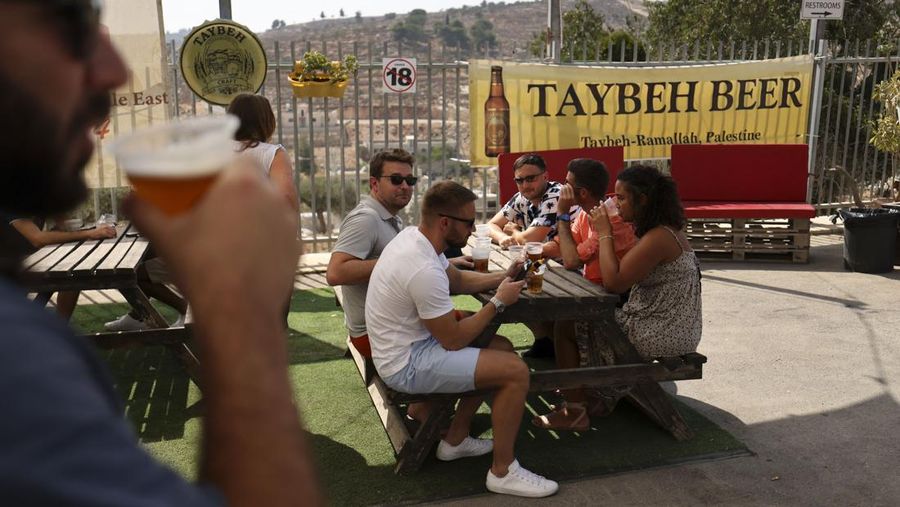 Seorang bartender melayani pengunjung pada festival bir tahunan Oktoberfest di desa Taybeh di desa Taybeh, sebelah timur kota Ramallah Tepi Barat, Palestina, Jumat (2/92/2022). Bir Taybeh dibuat dari buah anggur yang tumbuh di kebun anggur dekat Kota Birzeit, West Bank, sekitar 10 kilometer timur laut Ramallah. Bir Taybeh diseduh dalam jumlah kecil, tanpa menggunakan bahan pengawet atau gula tambahan. Taybeh Brewing Company didirikan oleh Nadim Khoury dan keluarganya pada 1994 di West Bank, Palestina dan kini diteruskan oleh seorang wanita bernama Madees Khoury, (Photo by ABBAS MOMANI/AFP via Getty Images).