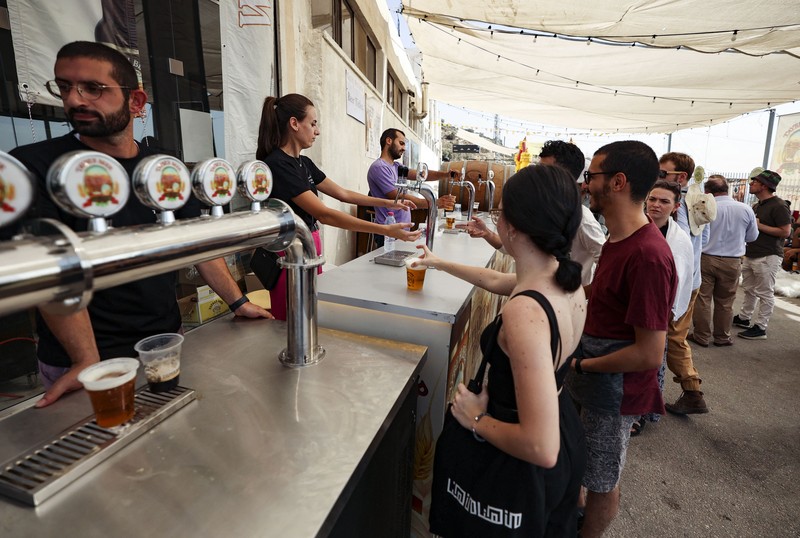Bir Halal Palestina Taybeh Seorang bartender melayani pengunjung pada festival bir tahunan Oktoberfest di desa Taybeh di desa Taybeh, sebelah timur kota Ramallah Tepi Barat, Palestina, Jumat (2/92/2022). Bir Taybeh dibuat dari buah anggur yang tumbuh di kebun anggur dekat Kota Birzeit, West Bank, sekitar 10 kilometer timur laut Ramallah. Bir Taybeh diseduh dalam jumlah kecil, tanpa menggunakan bahan pengawet atau gula tambahan. Taybeh Brewing Company didirikan oleh Nadim Khoury dan keluarganya pada 1994 di West Bank, Palestina dan kini diteruskan oleh seorang wanita bernama Madees Khoury, (Photo by ABBAS MOMANI/AFP via Getty Images).