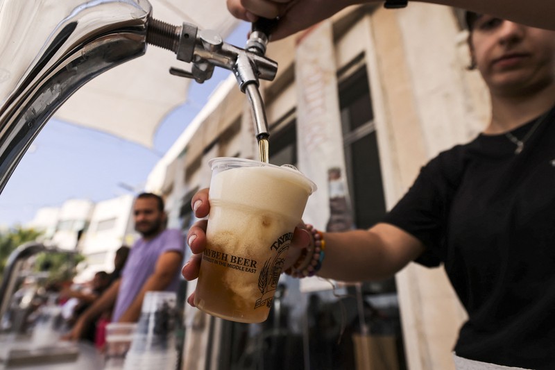 Bir Halal Palestina Taybeh Seorang bartender melayani pengunjung pada festival bir tahunan Oktoberfest di desa Taybeh di desa Taybeh, sebelah timur kota Ramallah Tepi Barat, Palestina, Jumat (2/92/2022). Bir Taybeh dibuat dari buah anggur yang tumbuh di kebun anggur dekat Kota Birzeit, West Bank, sekitar 10 kilometer timur laut Ramallah. Bir Taybeh diseduh dalam jumlah kecil, tanpa menggunakan bahan pengawet atau gula tambahan. Taybeh Brewing Company didirikan oleh Nadim Khoury dan keluarganya pada 1994 di West Bank, Palestina dan kini diteruskan oleh seorang wanita bernama Madees Khoury, (Photo by ABBAS MOMANI/AFP via Getty Images).