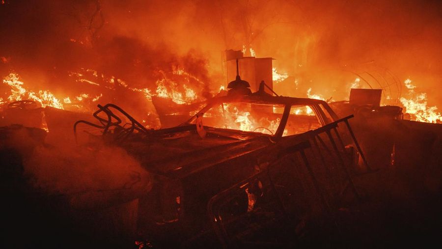 Sebuah pesawat pemadam kebakaran bekerja memadamkan api yang telah mendekati rumah selama Kebakaran hutan Fairview dekat Hemet, California di Riverside County, AS, Rabu (7/9/2022). Kebakaran hutan akibat gelombang panas di California, Amerika Serikat (AS), terus meluas dengan cepat. Kejadian tersebut menyebabkan dua orang tewas dan ribuan orang dievakuasi untuk mengungsi.  (Photo by PATRICK T. FALLON/AFP via Getty Images)