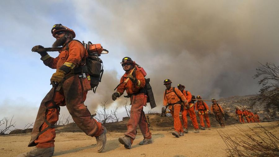 Sebuah pesawat pemadam kebakaran bekerja memadamkan api yang telah mendekati rumah selama Kebakaran hutan Fairview dekat Hemet, California di Riverside County, AS, Rabu (7/9/2022). Kebakaran hutan akibat gelombang panas di California, Amerika Serikat (AS), terus meluas dengan cepat. Kejadian tersebut menyebabkan dua orang tewas dan ribuan orang dievakuasi untuk mengungsi.  (Photo by PATRICK T. FALLON/AFP via Getty Images)