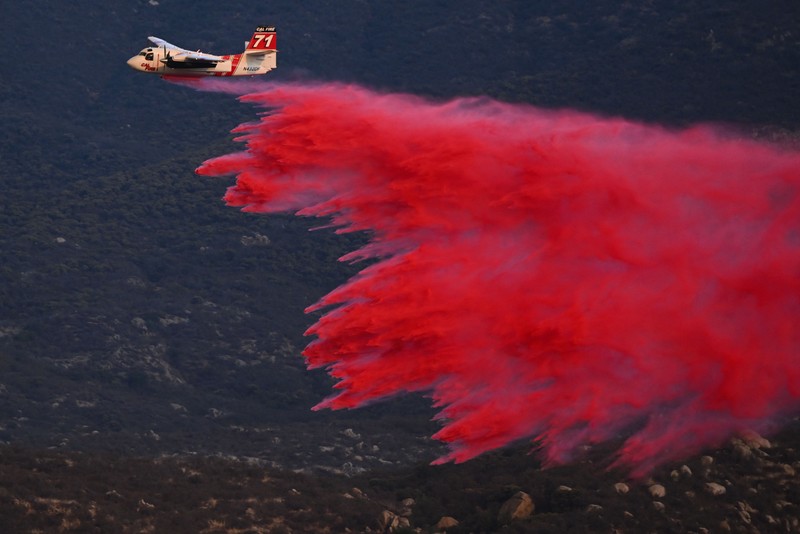 Kebakaran Hutan Fairview di Riverside County, California, AS Sebuah pesawat pemadam kebakaran bekerja memadamkan api yang telah mendekati rumah selama Kebakaran hutan Fairview dekat Hemet, California di Riverside County, AS, Rabu (7/9/2022). Kebakaran hutan akibat gelombang panas di California, Amerika Serikat (AS), terus meluas dengan cepat. Kejadian tersebut menyebabkan dua orang tewas dan ribuan orang dievakuasi untuk mengungsi. (Photo by PATRICK T. FALLON/AFP via Getty Images)