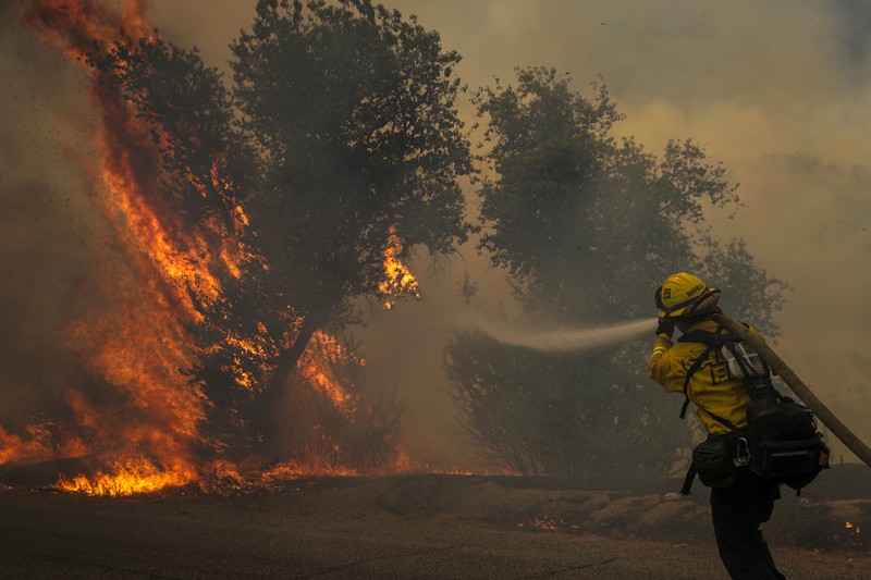Kebakaran Hutan Fairview di Riverside County, California, AS Sebuah pesawat pemadam kebakaran bekerja memadamkan api yang telah mendekati rumah selama Kebakaran hutan Fairview dekat Hemet, California di Riverside County, AS, Rabu (7/9/2022). Kebakaran hutan akibat gelombang panas di California, Amerika Serikat (AS), terus meluas dengan cepat. Kejadian tersebut menyebabkan dua orang tewas dan ribuan orang dievakuasi untuk mengungsi. (Photo by PATRICK T. FALLON/AFP via Getty Images)