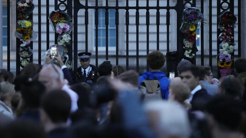 Personil menempatkan tanda yang mengumumkan meninggalnya Ratu Elizabeth di pagar di luar Istana Buckingham, London, Inggris, Kamis (8/9/2022). Ratu Elizabeth yang merupakan raja terlama yang memerintah Inggris dan tokoh negara selama tujuh dekade meninggal dalam usia 96 tahun.( REUTERS/Henry Nicholls)