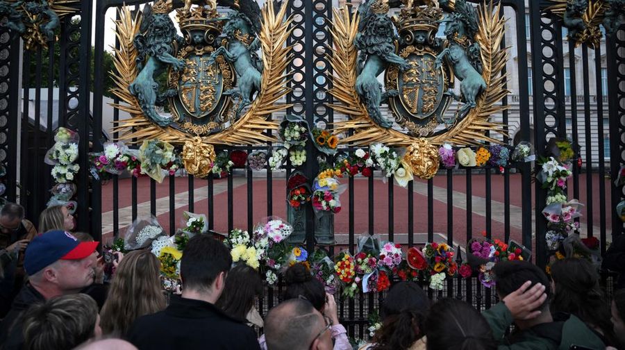 Orang-orang meletakan bunga sebagai tanda ucapan belasungkawa atas meninggalnya Ratu Elizabeth yang diletakkan di gerbang Istana Buckingham, London, Inggris, Kamis (8/9/2022). Ratu Elizabeth yang merupakan pemimpin terlama yang memerintah Inggris dan tokoh negara selama tujuh dekade meninggal dalam usia 96 tahun. (Photo by DANIEL LEAL/AFP via Getty Images)