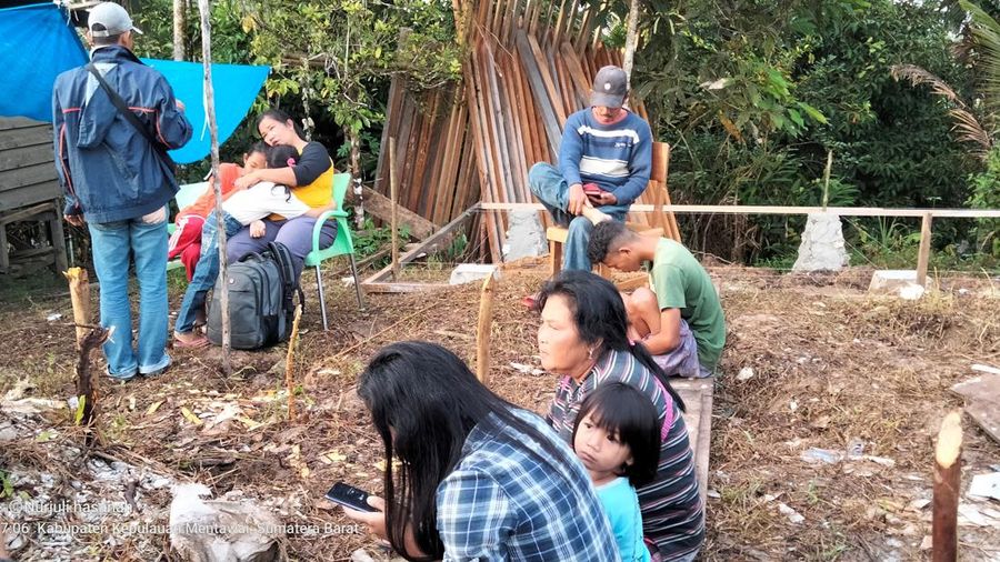 Warga berkumpul di luar rumah mereka setelah gempa bumi di Kepulauan Mentawai Indonesia, di desa Muara Sikabaluan di Siberut Utara, provinsi Sumatera Barat, Minggu (11/9/2022). (Photo by BAMBANG SAGURUNG/AFP via Getty Images)