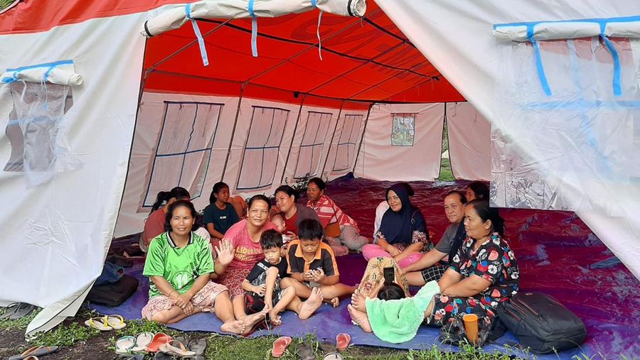 Warga berkumpul di luar rumah mereka setelah gempa bumi di Kepulauan Mentawai Indonesia, di desa Muara Sikabaluan di Siberut Utara, provinsi Sumatera Barat, Minggu (11/9/2022). (Photo by BAMBANG SAGURUNG/AFP via Getty Images)