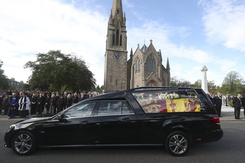 Mobil jenazah yang membawa peti mati Ratu Elizabeth Inggris meninggalkan Kastil Balmoral, di Balmoral, Skotlandia, Inggris ke Istana Holyroodhouse di Edinburgh Mobil jenazah membawa peti mati Ratu Elizabeth II yang ditutupi Standar Kerajaan untuk Skotlandia dan karangan bunga meninggalkan Kastil Balmoral, di Balmoral, Skotlandia, Inggris, Minggu (11/9/2022). Peti mati ratu akan dibawa sejauh 290 km melalui jalan darat dari perkebunan terpencil ke Istana Holyroodhouse di Edinburgh. (Photo by Owen Humphreys/PA Images via Getty Images)