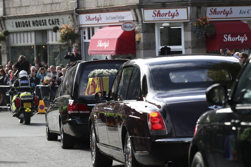 Mobil jenazah yang membawa peti mati Ratu Elizabeth Inggris meninggalkan Kastil Balmoral, di Balmoral, Skotlandia, Inggris ke Istana Holyroodhouse di Edinburgh Mobil jenazah membawa peti mati Ratu Elizabeth II yang ditutupi Standar Kerajaan untuk Skotlandia dan karangan bunga meninggalkan Kastil Balmoral, di Balmoral, Skotlandia, Inggris, Minggu (11/9/2022). Peti mati ratu akan dibawa sejauh 290 km melalui jalan darat dari perkebunan terpencil ke Istana Holyroodhouse di Edinburgh. (Photo by Owen Humphreys/PA Images via Getty Images)