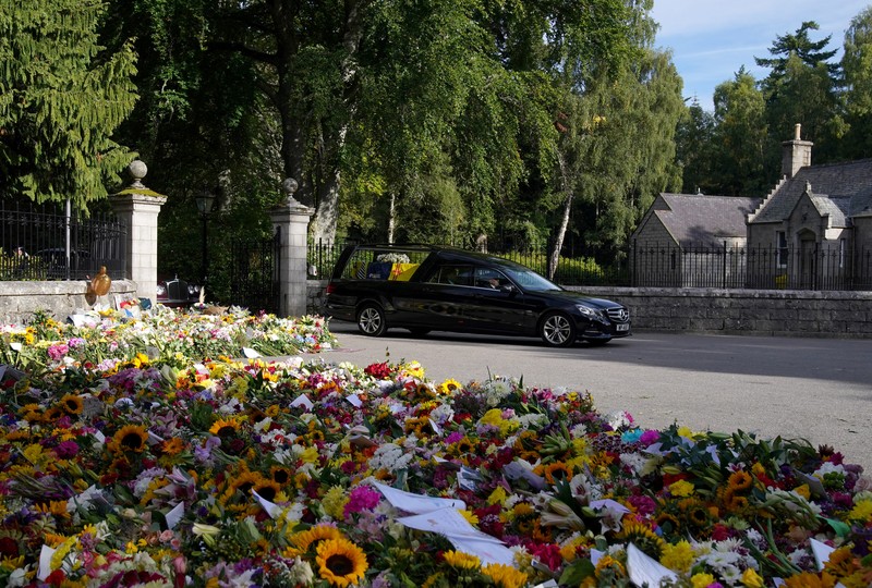 Mobil jenazah yang membawa peti mati Ratu Elizabeth Inggris meninggalkan Kastil Balmoral, di Balmoral, Skotlandia, Inggris ke Istana Holyroodhouse di Edinburgh Mobil jenazah membawa peti mati Ratu Elizabeth II yang ditutupi Standar Kerajaan untuk Skotlandia dan karangan bunga meninggalkan Kastil Balmoral, di Balmoral, Skotlandia, Inggris, Minggu (11/9/2022). Peti mati ratu akan dibawa sejauh 290 km melalui jalan darat dari perkebunan terpencil ke Istana Holyroodhouse di Edinburgh. (Photo by Owen Humphreys/PA Images via Getty Images)