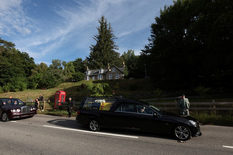Mobil jenazah yang membawa peti mati Ratu Elizabeth Inggris meninggalkan Kastil Balmoral, di Balmoral, Skotlandia, Inggris ke Istana Holyroodhouse di Edinburgh Mobil jenazah membawa peti mati Ratu Elizabeth II yang ditutupi Standar Kerajaan untuk Skotlandia dan karangan bunga meninggalkan Kastil Balmoral, di Balmoral, Skotlandia, Inggris, Minggu (11/9/2022). Peti mati ratu akan dibawa sejauh 290 km melalui jalan darat dari perkebunan terpencil ke Istana Holyroodhouse di Edinburgh. (Photo by Owen Humphreys/PA Images via Getty Images)
