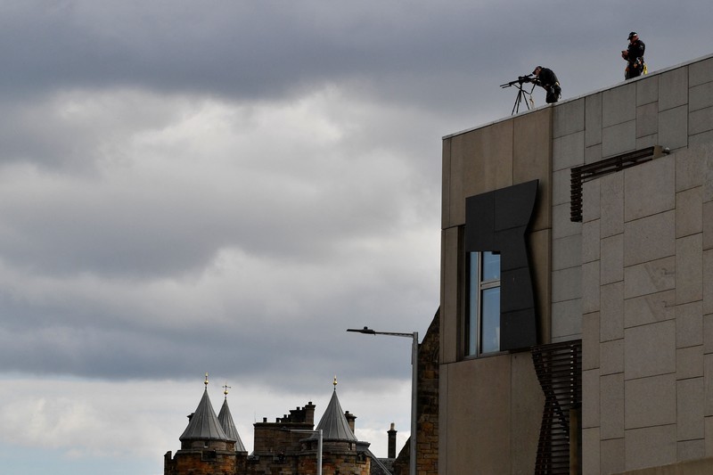 Police officers with snipers stand on the roof of the St Giles' Cathedral in Edinburgh on September 11, 2022, where Queen Elizabeth II will lie at rest and ahead of the ceremony of the proclamation of Britain's King Charles III. - Queen Elizabeth II's coffin will travel by road through Scottish towns and villages on Sunday as it begins its final journey from her beloved Scottish retreat of Balmoral. The Queen, who died on September 8, will be taken to the Palace of Holyroodhouse before lying at rest in St Giles' Cathedral, before travelling onwards to London for her funeral. (Photo by Oli SCARFF / AFP) (Photo by OLI SCARFF/AFP via Getty Images)