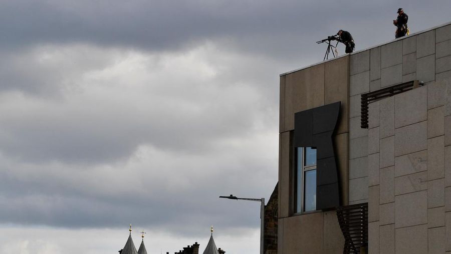 Police officers with snipers stand on the roof of the St Giles' Cathedral in Edinburgh on September 11, 2022, where Queen Elizabeth II will lie at rest and ahead of the ceremony of the proclamation of Britain's King Charles III. - Queen Elizabeth II's coffin will travel by road through Scottish towns and villages on Sunday as it begins its final journey from her beloved Scottish retreat of Balmoral. The Queen, who died on September 8, will be taken to the Palace of Holyroodhouse before lying at rest in St Giles' Cathedral, before travelling onwards to London for her funeral. (Photo by Oli SCARFF / AFP) (Photo by OLI SCARFF/AFP via Getty Images)