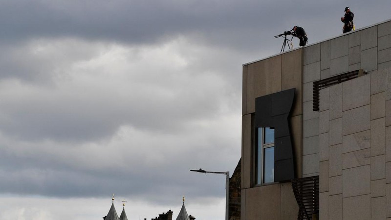 Police officers with snipers stand on the roof of the St Giles' Cathedral in Edinburgh on September 11, 2022, where Queen Elizabeth II will lie at rest and ahead of the ceremony of the proclamation of Britain's King Charles III. - Queen Elizabeth II's coffin will travel by road through Scottish towns and villages on Sunday as it begins its final journey from her beloved Scottish retreat of Balmoral. The Queen, who died on September 8, will be taken to the Palace of Holyroodhouse before lying at rest in St Giles' Cathedral, before travelling onwards to London for her funeral. (Photo by Oli SCARFF / AFP) (Photo by OLI SCARFF/AFP via Getty Images)