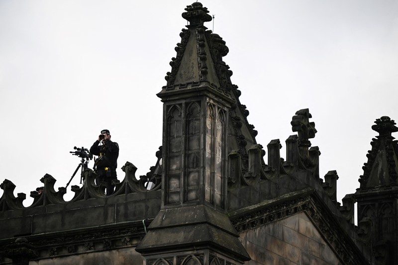 Police officers with snipers stand on the roof of the St Giles' Cathedral in Edinburgh on September 11, 2022, where Queen Elizabeth II will lie at rest and ahead of the ceremony of the proclamation of Britain's King Charles III. - Queen Elizabeth II's coffin will travel by road through Scottish towns and villages on Sunday as it begins its final journey from her beloved Scottish retreat of Balmoral. The Queen, who died on September 8, will be taken to the Palace of Holyroodhouse before lying at rest in St Giles' Cathedral, before travelling onwards to London for her funeral. (Photo by Oli SCARFF / AFP) (Photo by OLI SCARFF/AFP via Getty Images)