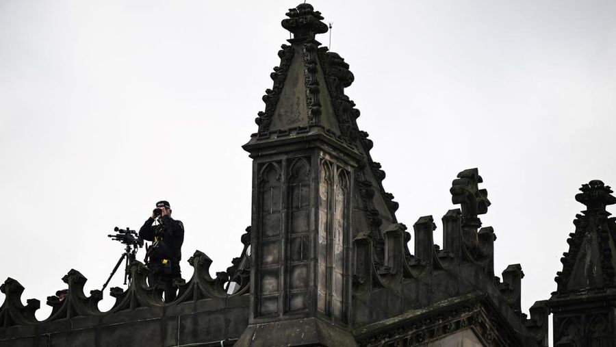 Police officers with snipers stand on the roof of the St Giles' Cathedral in Edinburgh on September 11, 2022, where Queen Elizabeth II will lie at rest and ahead of the ceremony of the proclamation of Britain's King Charles III. - Queen Elizabeth II's coffin will travel by road through Scottish towns and villages on Sunday as it begins its final journey from her beloved Scottish retreat of Balmoral. The Queen, who died on September 8, will be taken to the Palace of Holyroodhouse before lying at rest in St Giles' Cathedral, before travelling onwards to London for her funeral. (Photo by Oli SCARFF / AFP) (Photo by OLI SCARFF/AFP via Getty Images)