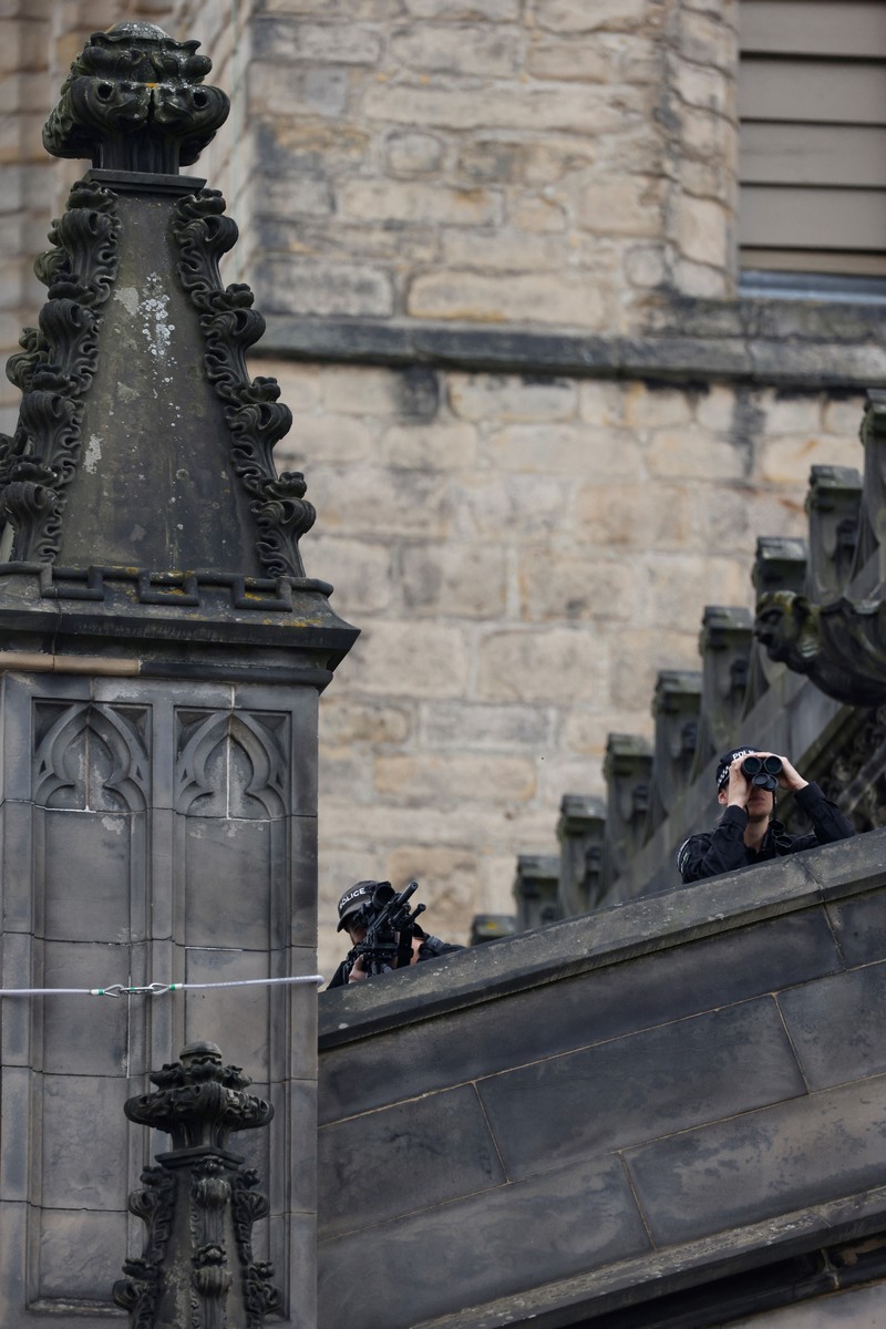 Police officers with snipers stand on the roof of the St Giles' Cathedral in Edinburgh on September 11, 2022, where Queen Elizabeth II will lie at rest and ahead of the ceremony of the proclamation of Britain's King Charles III. - Queen Elizabeth II's coffin will travel by road through Scottish towns and villages on Sunday as it begins its final journey from her beloved Scottish retreat of Balmoral. The Queen, who died on September 8, will be taken to the Palace of Holyroodhouse before lying at rest in St Giles' Cathedral, before travelling onwards to London for her funeral. (Photo by Oli SCARFF / AFP) (Photo by OLI SCARFF/AFP via Getty Images)