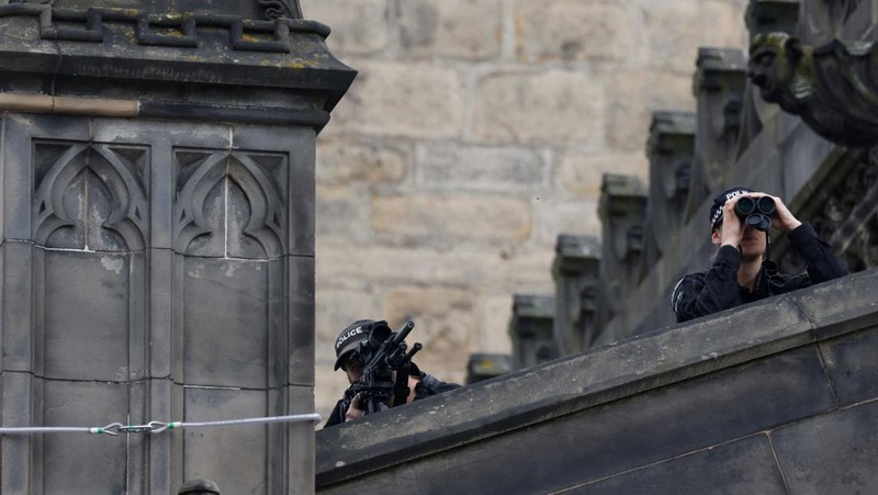 Police officers with snipers stand on the roof of the St Giles' Cathedral in Edinburgh on September 11, 2022, where Queen Elizabeth II will lie at rest and ahead of the ceremony of the proclamation of Britain's King Charles III. - Queen Elizabeth II's coffin will travel by road through Scottish towns and villages on Sunday as it begins its final journey from her beloved Scottish retreat of Balmoral. The Queen, who died on September 8, will be taken to the Palace of Holyroodhouse before lying at rest in St Giles' Cathedral, before travelling onwards to London for her funeral. (Photo by Oli SCARFF / AFP) (Photo by OLI SCARFF/AFP via Getty Images)