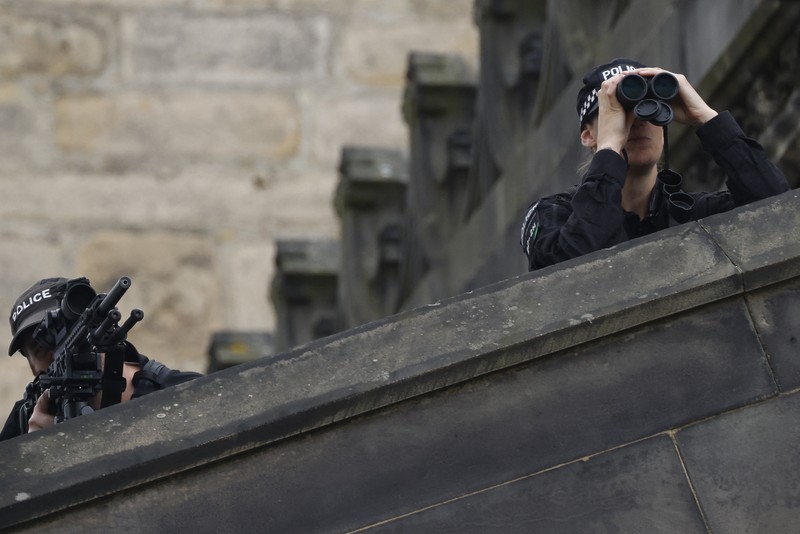 Police officers with snipers stand on the roof of the St Giles' Cathedral in Edinburgh on September 11, 2022, where Queen Elizabeth II will lie at rest and ahead of the ceremony of the proclamation of Britain's King Charles III. - Queen Elizabeth II's coffin will travel by road through Scottish towns and villages on Sunday as it begins its final journey from her beloved Scottish retreat of Balmoral. The Queen, who died on September 8, will be taken to the Palace of Holyroodhouse before lying at rest in St Giles' Cathedral, before travelling onwards to London for her funeral. (Photo by Oli SCARFF / AFP) (Photo by OLI SCARFF/AFP via Getty Images)
