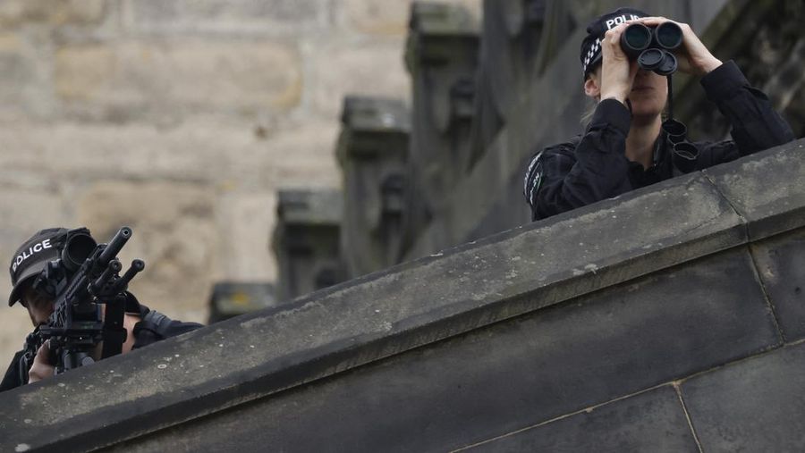 Police officers with snipers stand on the roof of the St Giles' Cathedral in Edinburgh on September 11, 2022, where Queen Elizabeth II will lie at rest and ahead of the ceremony of the proclamation of Britain's King Charles III. - Queen Elizabeth II's coffin will travel by road through Scottish towns and villages on Sunday as it begins its final journey from her beloved Scottish retreat of Balmoral. The Queen, who died on September 8, will be taken to the Palace of Holyroodhouse before lying at rest in St Giles' Cathedral, before travelling onwards to London for her funeral. (Photo by Oli SCARFF / AFP) (Photo by OLI SCARFF/AFP via Getty Images)