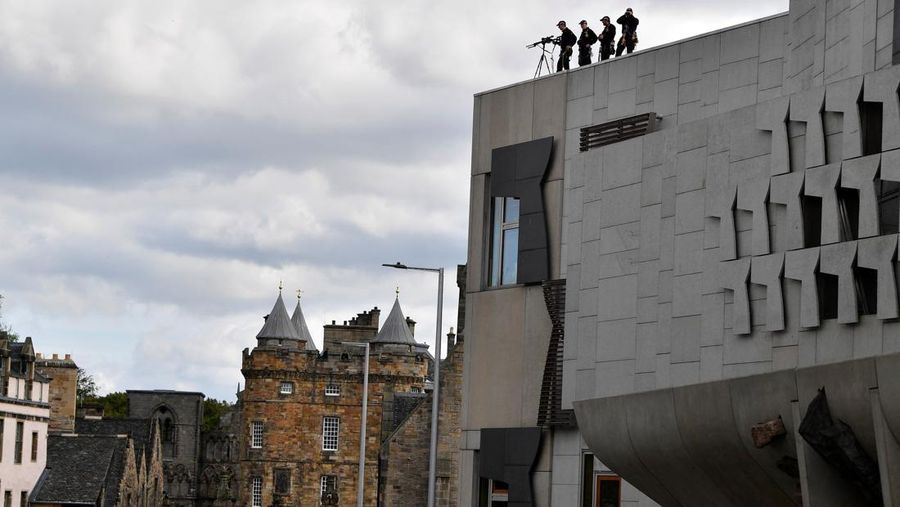 Police officers with snipers stand on the roof of the St Giles' Cathedral in Edinburgh on September 11, 2022, where Queen Elizabeth II will lie at rest and ahead of the ceremony of the proclamation of Britain's King Charles III. - Queen Elizabeth II's coffin will travel by road through Scottish towns and villages on Sunday as it begins its final journey from her beloved Scottish retreat of Balmoral. The Queen, who died on September 8, will be taken to the Palace of Holyroodhouse before lying at rest in St Giles' Cathedral, before travelling onwards to London for her funeral. (Photo by Oli SCARFF / AFP) (Photo by OLI SCARFF/AFP via Getty Images)