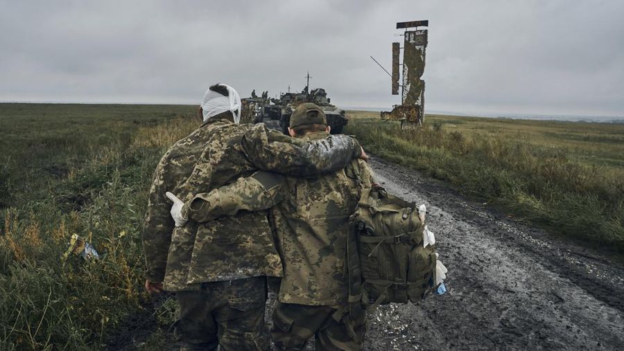 A Ukrainian soldier helps a wounded fellow soldier on the road in the freed territory in the Kharkiv region, Ukraine, Monday, Sept. 12, 2022. Ukrainian troops retook a wide swath of territory from Russia on Monday, pushing all the way back to the northeastern border in some places, and claimed to have captured many Russian soldiers as part of a lightning advance that forced Moscow to make a hasty retreat. (AP Photo/Kostiantyn Liberov)