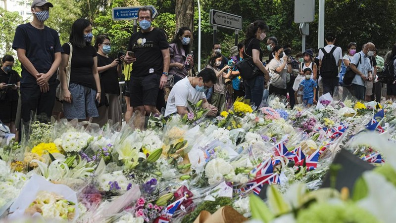 People queue to sign a condolence book next to flowers placed as a tribute outside the British Consulate in Hong Kong on September 12, 2022, following the death of Britain's Queen Elizabeth II. (Photo by Peter PARKS / AFP) (Photo by PETER PARKS/AFP via Getty Images)