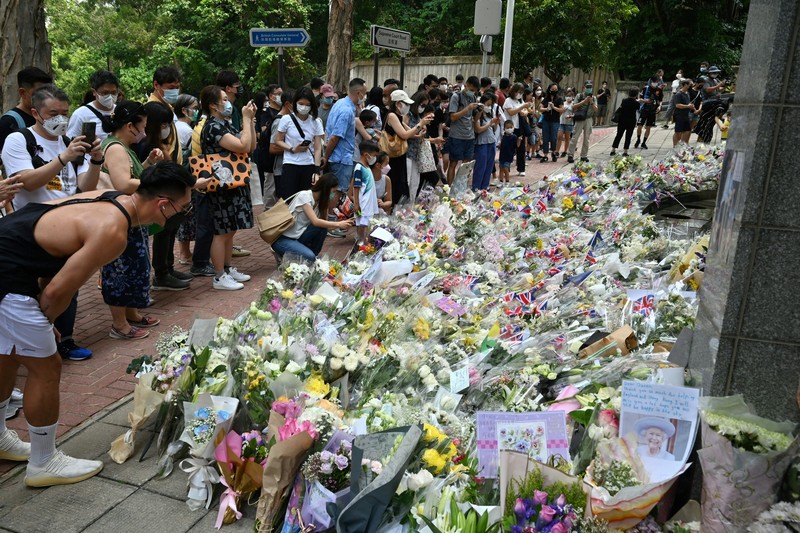 1243159136 People queue to sign a condolence book next to flowers placed as a tribute outside the British Consulate in Hong Kong on September 12, 2022, following the death of Britain's Queen Elizabeth II. (Photo by Peter PARKS / AFP) (Photo by PETER PARKS/AFP via Getty Images)