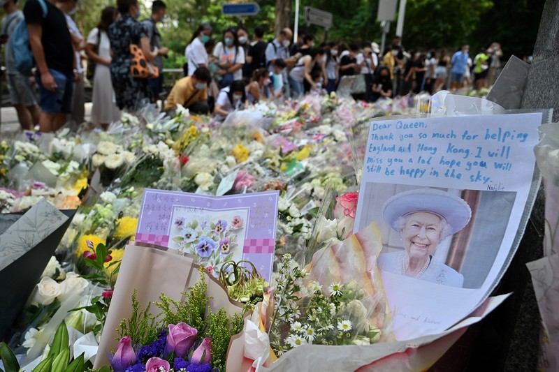 1243159136 People queue to sign a condolence book next to flowers placed as a tribute outside the British Consulate in Hong Kong on September 12, 2022, following the death of Britain's Queen Elizabeth II. (Photo by Peter PARKS / AFP) (Photo by PETER PARKS/AFP via Getty Images)