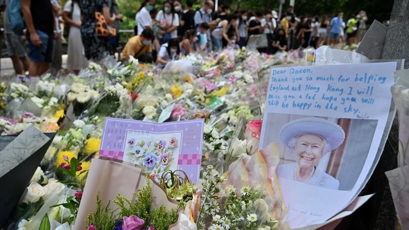 People queue to sign a condolence book next to flowers placed as a tribute outside the British Consulate in Hong Kong on September 12, 2022, following the death of Britain's Queen Elizabeth II. (Photo by Peter PARKS / AFP) (Photo by PETER PARKS/AFP via Getty Images)