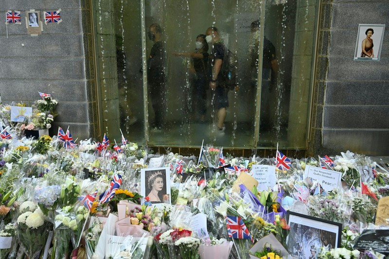 People queue to sign a condolence book next to flowers placed as a tribute outside the British Consulate in Hong Kong on September 12, 2022, following the death of Britain's Queen Elizabeth II. (Photo by Peter PARKS / AFP) (Photo by PETER PARKS/AFP via Getty Images)