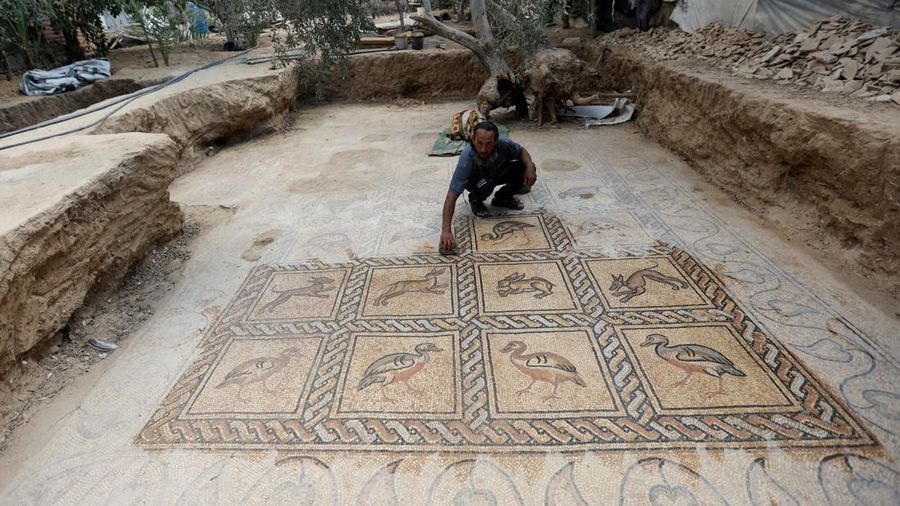 Petani Palestina Salman al-Nabahin membersihkan lantai mosaik yang ia temukan di pertaniannya dan berasal dari era Bizantium, menurut para pejabat, di Jalur Gaza tengah 18 September 2022. (REUTERS/IBRAHEEM ABU MUSTAFA)