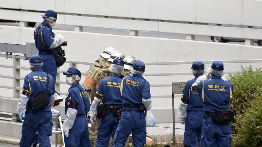 Petugas polisi dan petugas pemadam kebakaran menyelidiki di lokasi di mana seorang pria yang memprotes pemakaman kenegaraan untuk mantan Perdana Menteri Jepang Shinzo Abe membakar dirinya sendiri, di dekat kediaman resmi Perdana Menteri Fumio Kishida di Tokyo, Jepang 21 September 2022. (via REUTERS/KYODO)