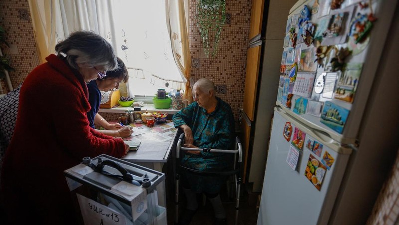 Penduduk lokal Valentina (90) menunggu sebelum menerima surat suara dari anggota komisi pemilihan, yang mengunjungi apartemen dengan kotak suara dan dokumen pada hari ketiga referendum tentang bergabungnya Republik Rakyat Donetsk (DPR) yang memproklamirkan diri ke Rusia, di Mariupol, Ukraina, Minggu (25/9/2022). (REUTERS/Alexander Ermochenko)
